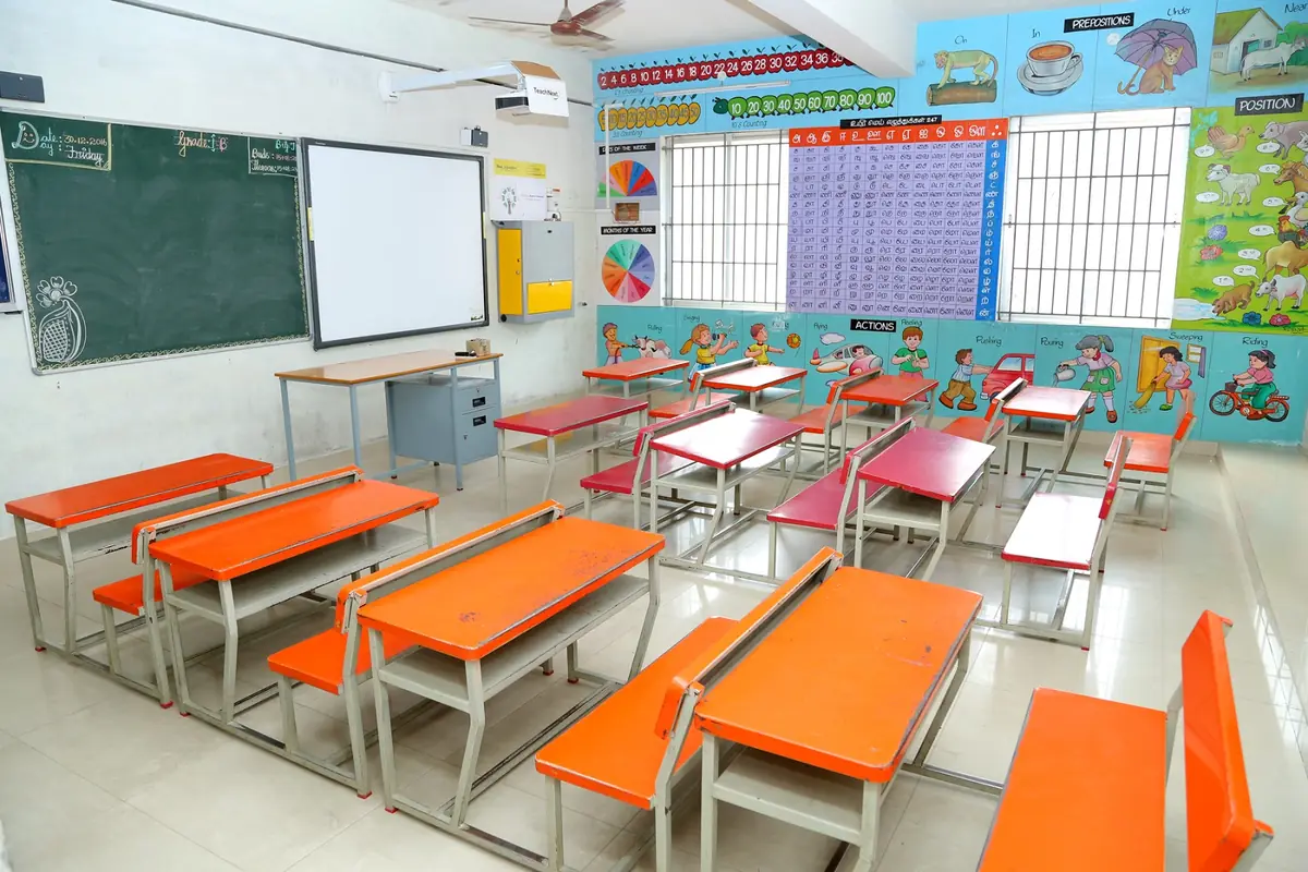 Bright classroom with green boards and student desks at Dheeran Academy